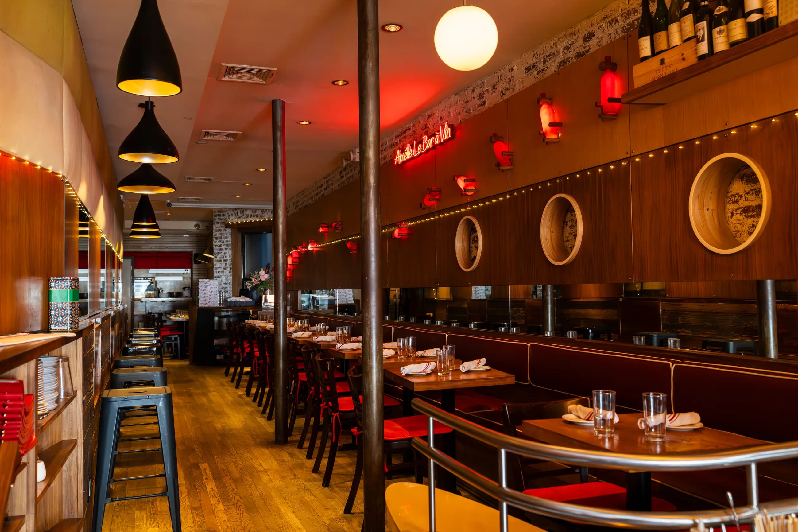 The front of the room at Amélie Upper West Side, the Amélie script sign glowing above the banquette