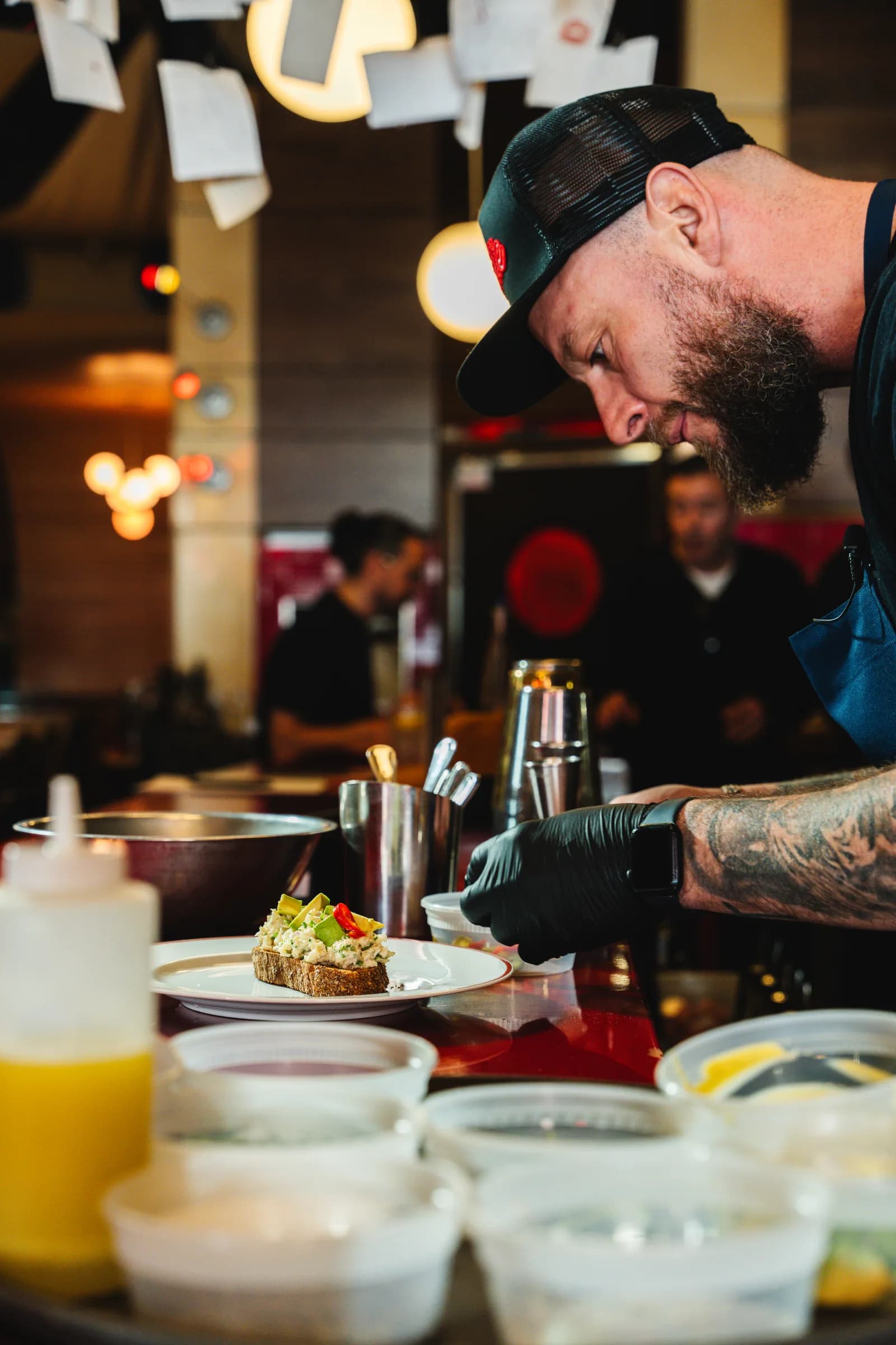 A chef finishing a tartine at the pass during service at Amélie West Village